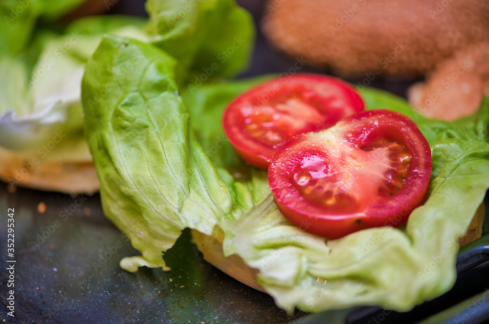 Tasty hamburger prepared on the table, closeup of tomatoes Tasty hamburger prepared on the table, closeup of tomatoes
