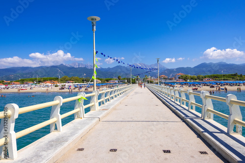 Forte dei Marmi, Italy - August 18, 2019: Pier, beach and Apuane mountains in Forte dei Marmi, Versilia coast, Tuscany, Italy