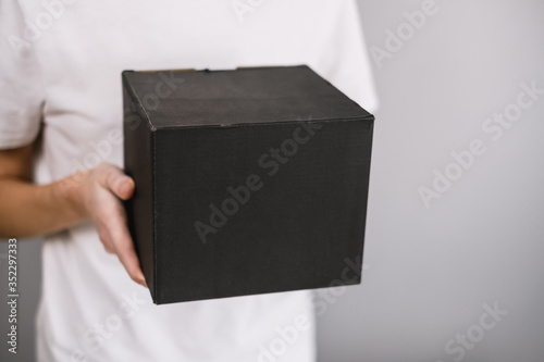 Woman holding a black cardboard box, the parcel in hands. Delivery concept, mock up. photo