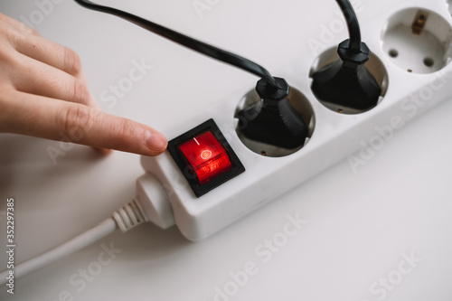 Obraz na płótnie A woman turns on an electric surge protector