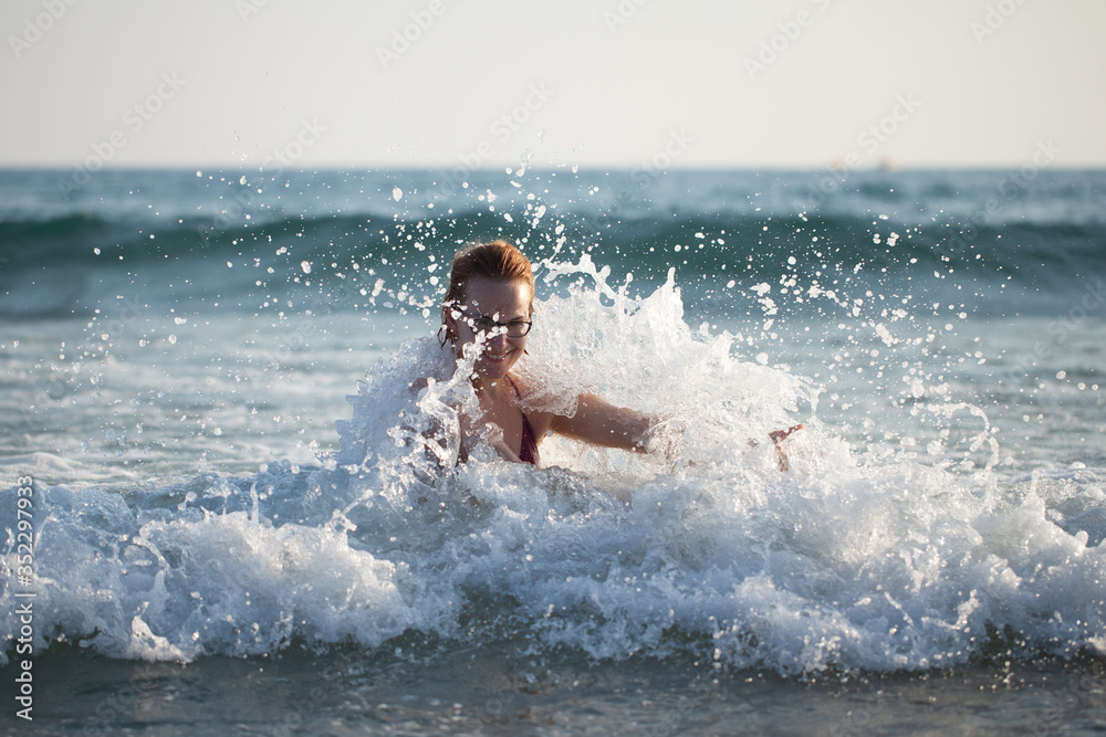 young beautiful girl swims in the sea waves