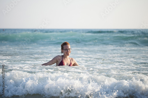 young beautiful girl swims in the sea waves