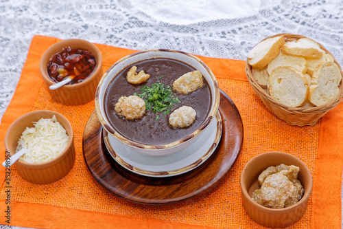 Caldo de feijão servido com torradas, torresmo e queijo ralado photo