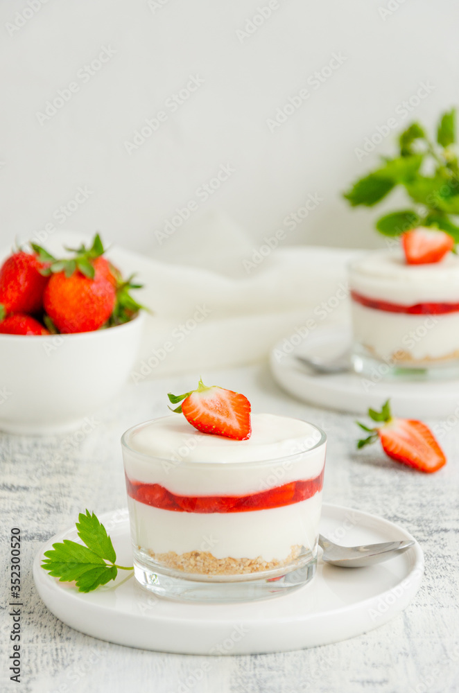 No baked strawberry cheesecake in a glass on a wooden background. Summer cold dessert. Vertical, copy space. No baked strawberry cheesecake in a glass on a wooden background. Summer cold dessert. Vertical, copy space.