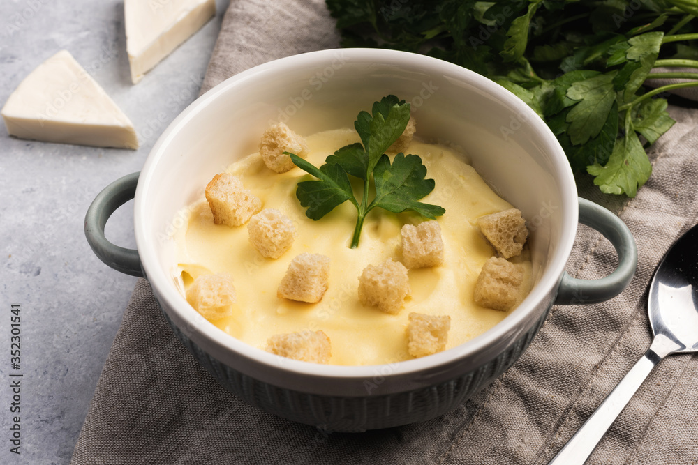 Cheese cream soup with croutons and parsley on gray marble Cheese cream soup with croutons and parsley on gray marble