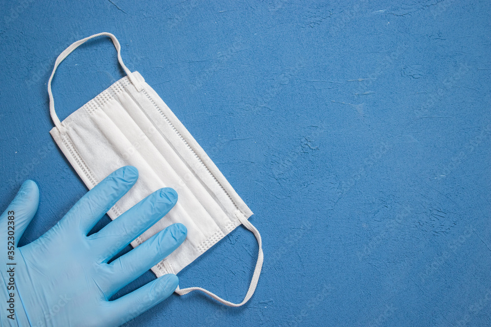Surgical medical mask and glove on blue isolated background. Coronavirus 2019-nCoV. Covid-19. Surgical medical mask and glove on blue isolated background. Coronavirus 2019-nCoV. Covid-19.