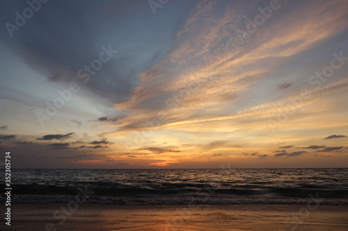 beautiful view of endless ocean with wide rolling waves against pictorial orange sky with clouds at exotic sunset