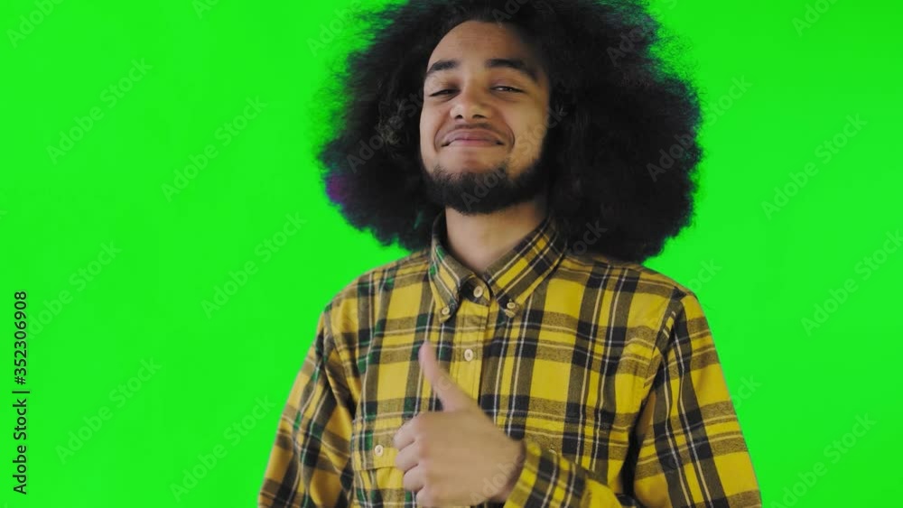 Young happy afro american man smiling while giving thumbs up on green screen or chroma key background. Concept of emotions Young happy afro american man smiling while giving thumbs up on green screen or chroma key background. Concept of emotions