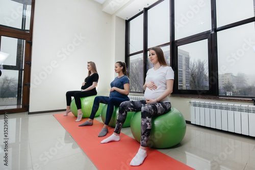 A group of young pregnant mothers are engaged in Pilates and ball sports at a fitness club. Pregnant