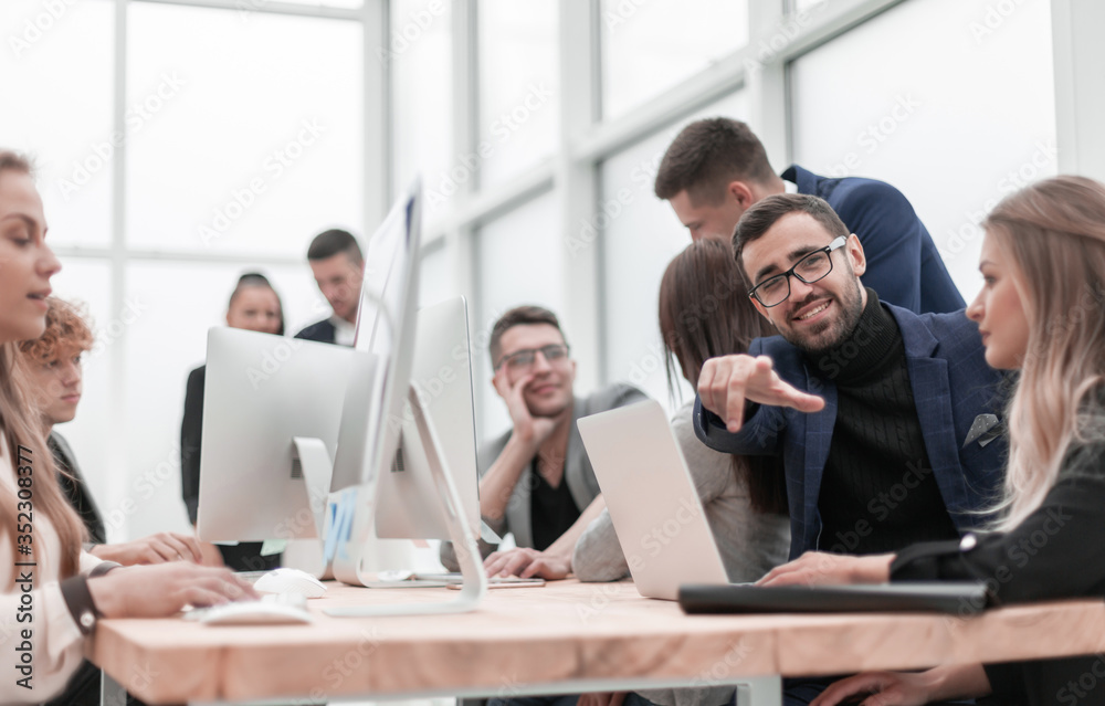 young businessman sitting at office Desk and pointing at you young businessman sitting at office Desk and pointing at you