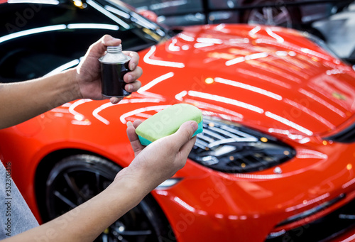 Car service worker applying nano coating on a car detail © romaset