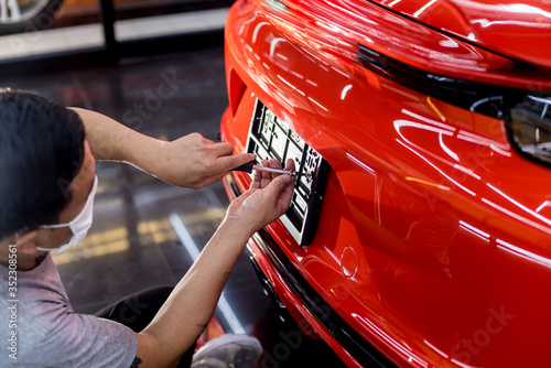 Wallpaper Mural Technician changing car plate number in service center. Torontodigital.ca