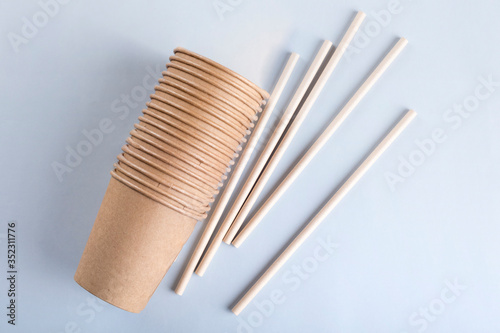Disposable cups and drinking straws on light grey background.