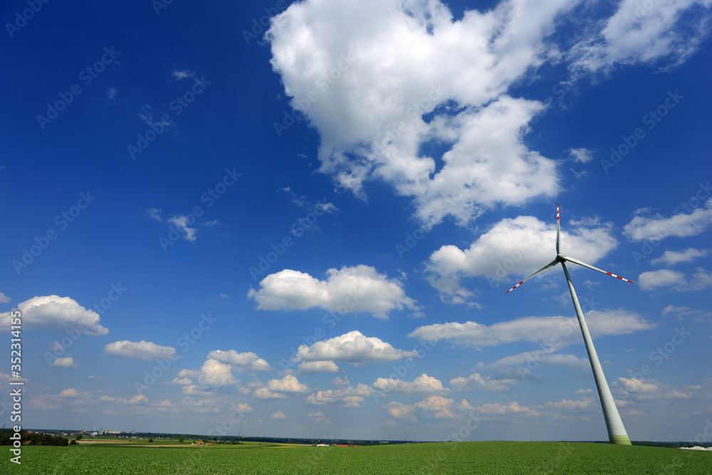 Turbina wiatrowa, wiatrak na zielonym polu, na tle niebieskiego nieba z chmurami. - obrazy, fototapety, plakaty 