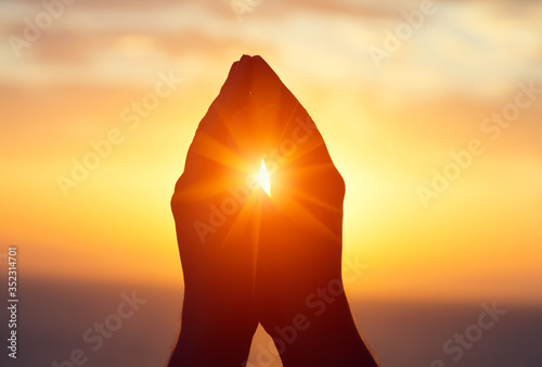 silhouette of male raising hands praying for God's blessings at sunset or sunrise light, practicing yoga on the beach, religion, freedom and spirituality concept