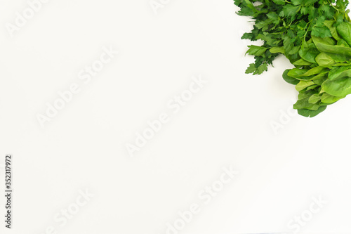 greens in the upper right corner of the white background, spinach and parsley