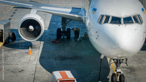 Professional mechanics in airport ground crew checking airplane chassis before flight