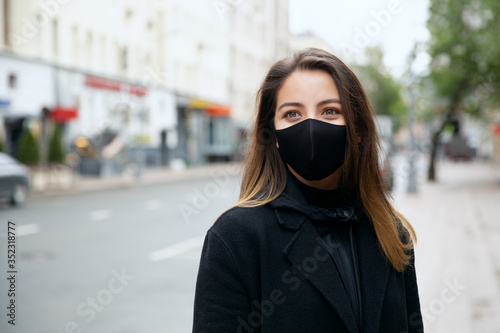 Portrait of beautiful girl with green eyes wearing black face mask on the street
