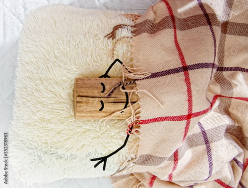 Canvas Print a rough piece of wood with a painted face and hands sleeping in bed on a pillow under a clothe embodying the phrase - sleeping like a log