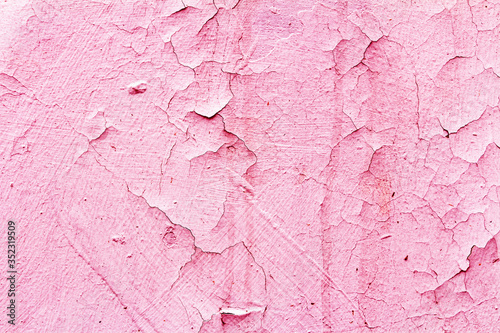 The rich pink paint on the rough concrete wall was peeling with age.