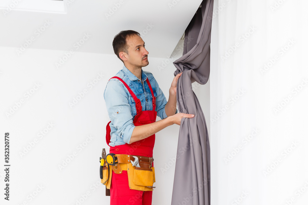 Handy man home Installation and repair service technician or home owner hanging curtains for the window treatment in a new house. - obrazy, fototapety, plakaty 