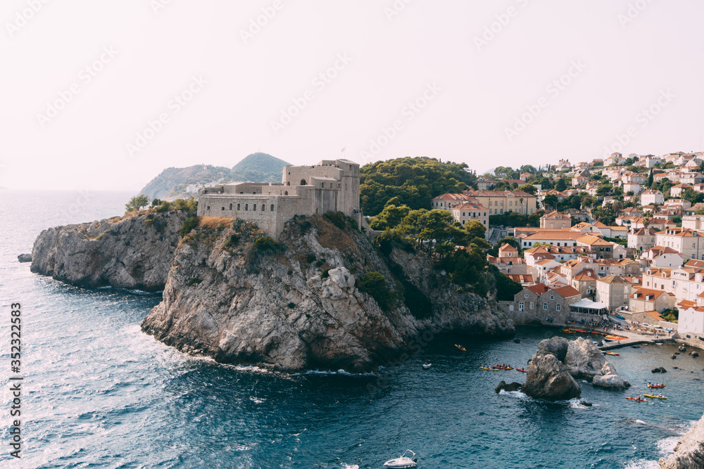 View from the wall of the old city of Dubrovnik on the fort Lovrijenac fortress on the cliff and the bay with a pier.