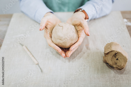 The potter's hands are shaped a cup from a clay. The process of creating pottery. The master ceramist works in his studio. Close-up, only hands. Crockery from clay own hands.	 photo