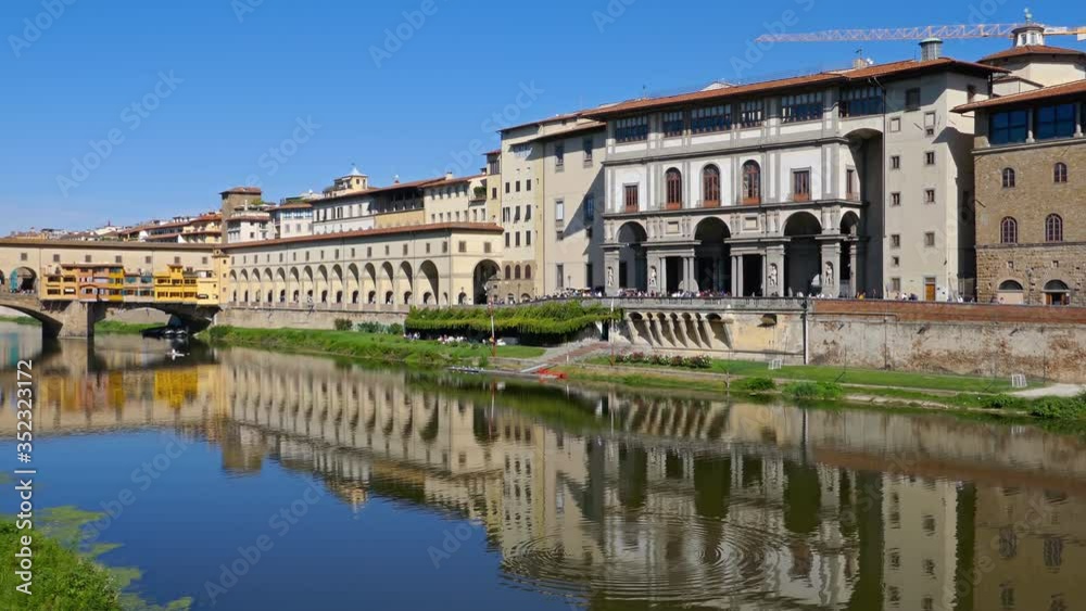 Walking in front of Uffizi and Ponte Vecchio, medieval stone bridge over of Arno river at clear summer day in Florence, Italy. Walking in front of Uffizi and Ponte Vecchio, medieval stone bridge over of Arno river at clear summer day in Florence, Italy.