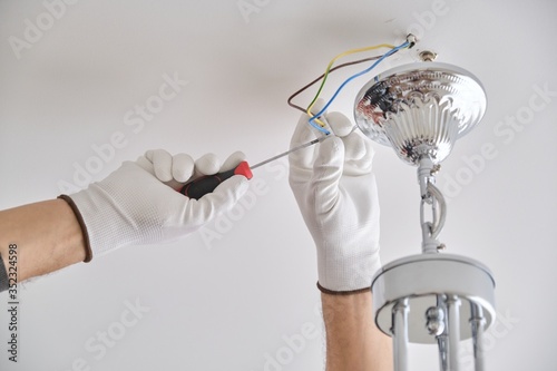 Installation ceiling lamp, hands of electrician fixing chandelier