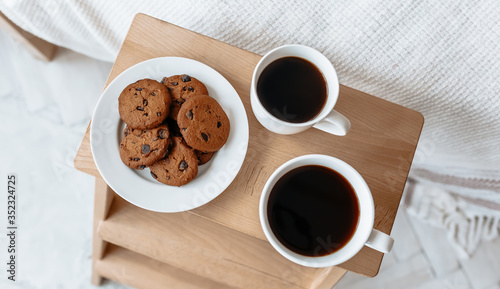 Breakfast in bed. Hot coffee with oatmeal cookies with chocolate on a wooden tray.