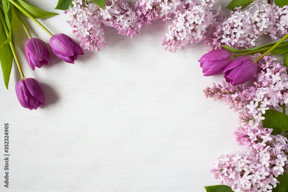Obraz premium Pink lilac flowers and purple tulips on a wooden background. Space for congratulations text.