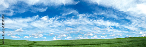 Sky blue with beautiful clouds and green meadow. Panoramic summer background.