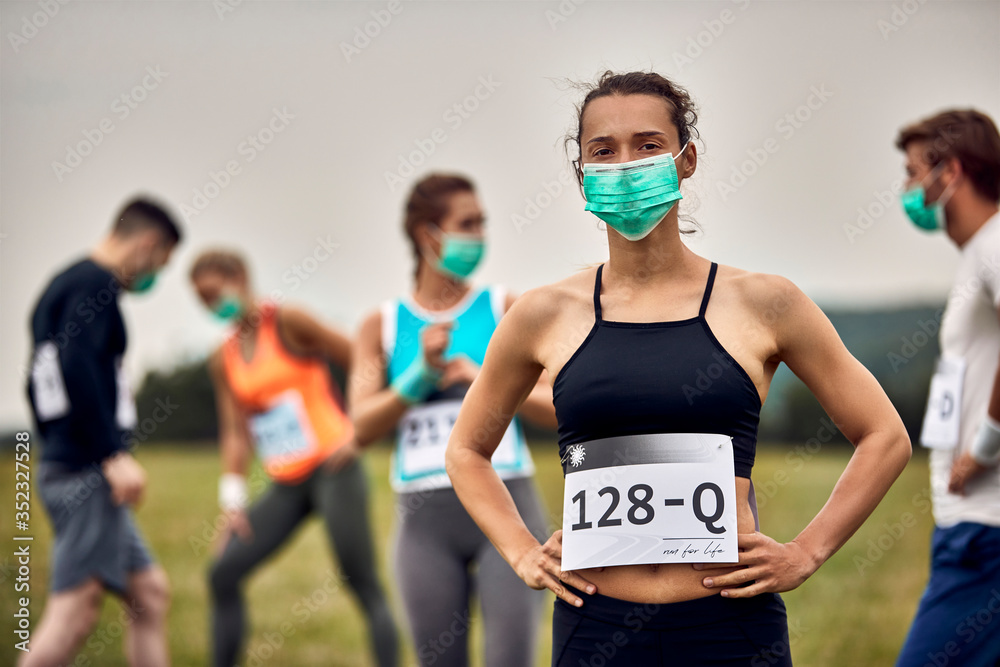 Naklejka premium Young sportswoman wearing face mask while participating in marathon race during coronavirus epidemic.