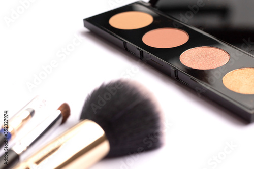 Three makeup brushes and highlighter on a white background. Cosmetical tools