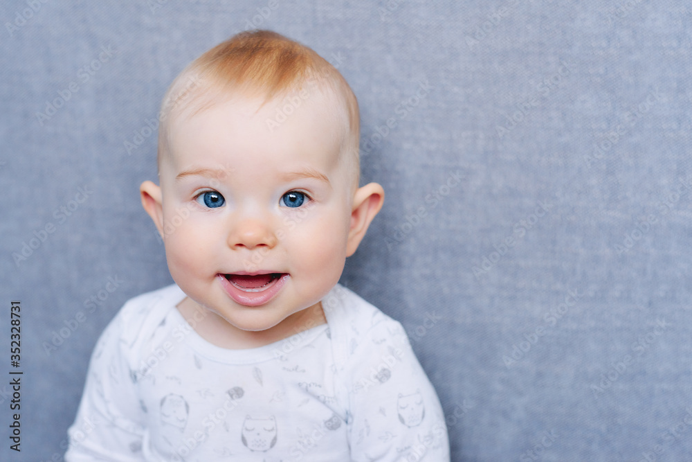 Naklejka premium portrait of a smiling baby on gray background
