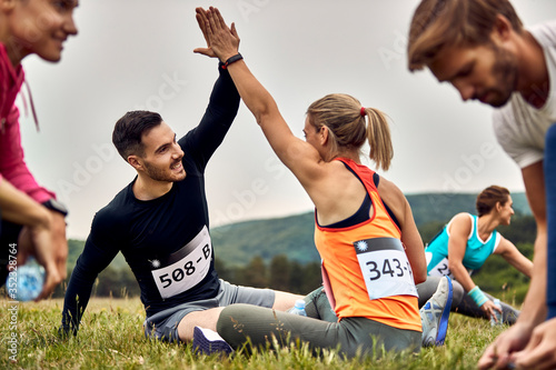 Happy athletic couple warming up before a marathon in nature.