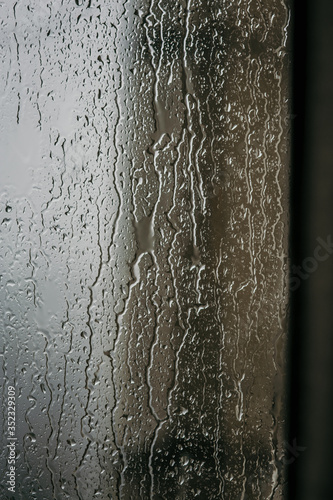Raindrops on glass, view from the window, heavy rain, bad weather, loneliness, isolation. The texture of the wet surface, background, beautiful wallpaper. Nature is crying.