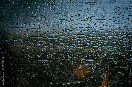 Raindrops on glass, view from the window, heavy rain, bad weather, loneliness, isolation. The texture of the wet surface, background, beautiful wallpaper. Nature is crying.