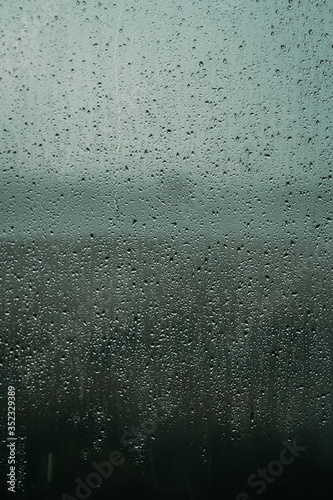 Raindrops on glass, view from the window, heavy rain, bad weather, loneliness, isolation. The texture of the wet surface, background, beautiful wallpaper. Nature is crying.