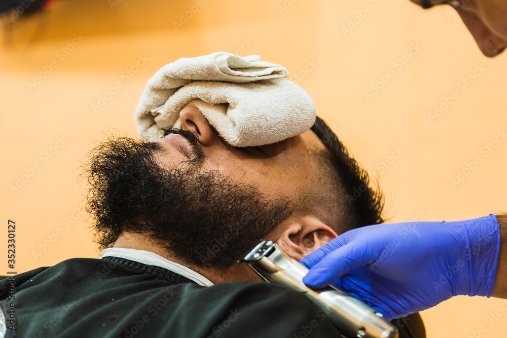 Fototapeta premium Closeup of a latex gloved hand, working the beard of a bearded man.
