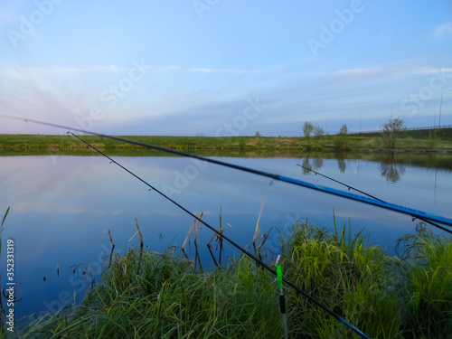 Fishing on a pond with fishing rods. Beautiful pond and fishing rods on the background of the pond. © marie_tatiant