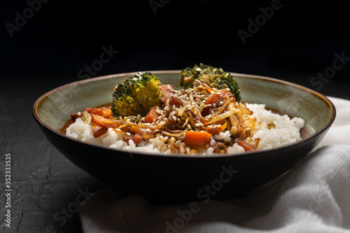 Thai style rice with fried vegetables and soy sauce on dark background