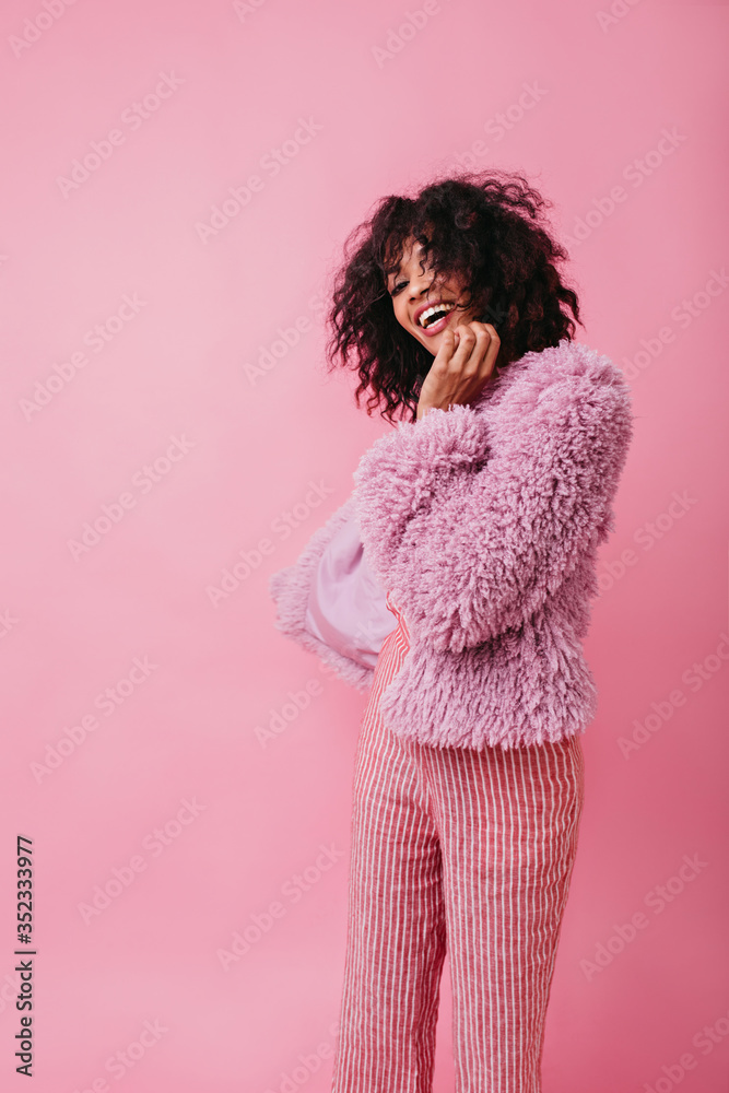 Portrait of cute spectacular African woman in stylish clothes. Model from America laughs wholeheartedly, covering her face with her hand Portrait of cute spectacular African woman in stylish clothes. Model from America laughs wholeheartedly, covering her face with her hand