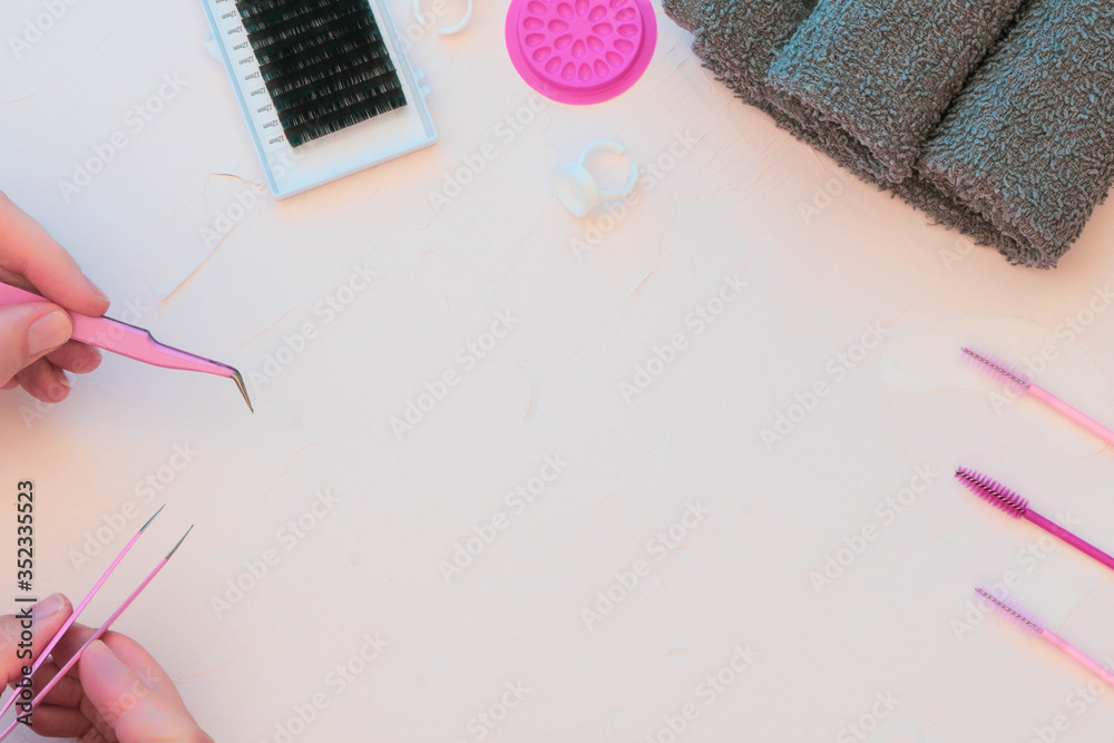 A beauty background in a flat lay style. Pink and grey colour theme with plain background. Woman's hands holding pink tweezers on left side of frame A beauty background in a flat lay style. Pink and grey colour theme with plain background. Woman's hands holding pink tweezers on left side of frame
