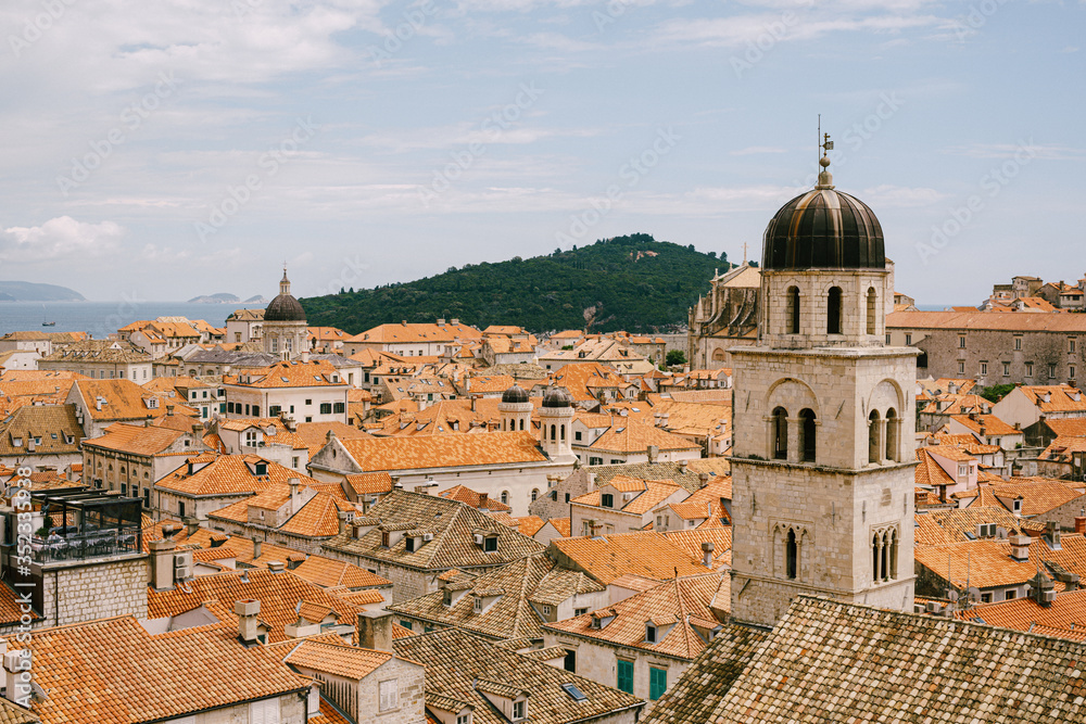 The bell tower of the Franciscan monastery in Dubrovnik against the background of the roofs of the city in the tiles.