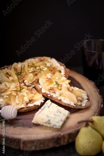 Pear and blue cheese toast with rosemary and honey on a dark and rustic background