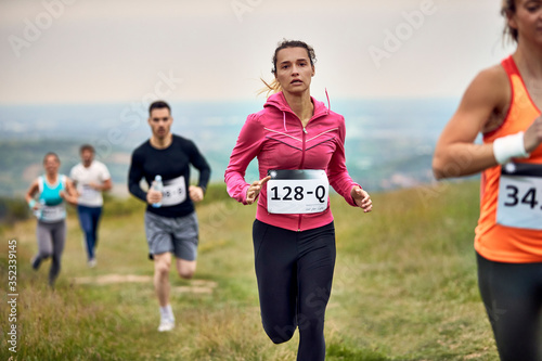 Young female athlete running marathon in nature.