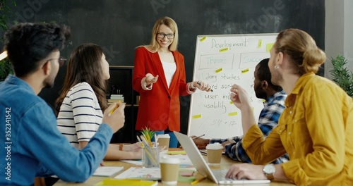 Картината върху платно Blonde pretty young woman finishing her report on business startup strategy and colleagues applauding