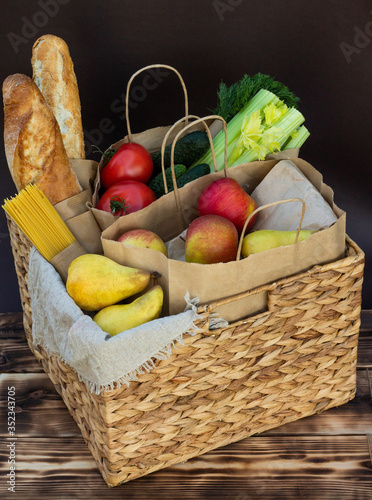 Fresh eco organic vegetables, greens and fruits, cereals and pasta in a wicker basket. Delivery or donation of ecological farm food concept.