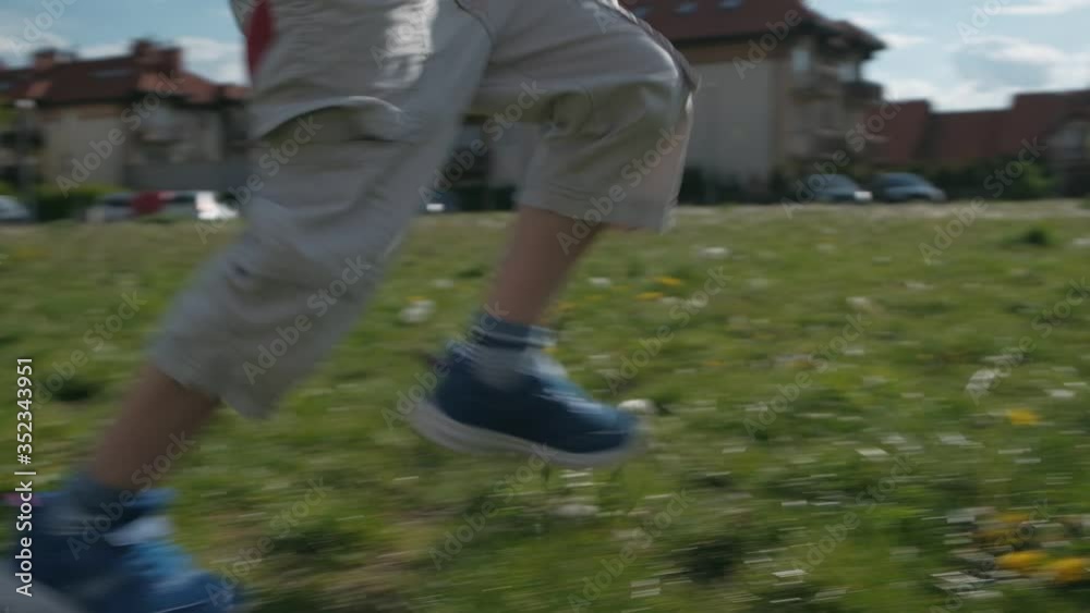 Boy playing football. Kid with the soccer ball runs through the green grass Boy playing football. Kid with the soccer ball runs through the green grass